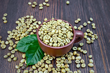 Image showing Coffee green grain in cup with leaf on dark board