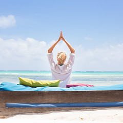 Image showing Relaxed woman in luxury lounger, arms rised, enjoying summer vacations on beautiful beach.