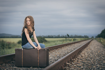 Image showing Portrait of young sad ten girl standing with suitcase outdoors a