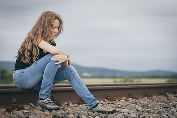 Image showing Portrait of young sad ten girl sitting outdoors at the day time.