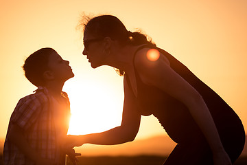 Image showing Mother and son walking on the field at the sunset time.