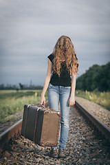 Image showing Portrait of young sad ten girl standing with suitcase outdoors a