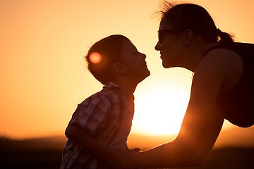 Image showing Mother and son walking on the field at the sunset time.