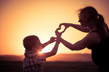 Image showing Mother and son walking on the field at the sunset time.