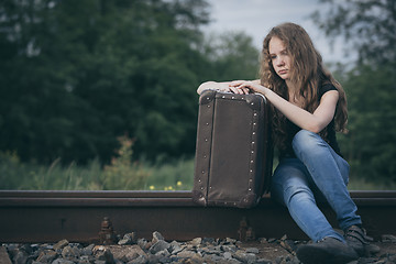 Image showing Portrait of young sad ten girl standing with suitcase outdoors a