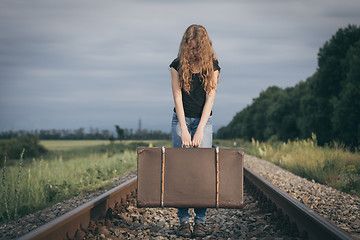 Image showing Portrait of young sad ten girl standing with suitcase outdoors a