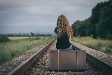 Image showing Portrait of young sad ten girl standing with suitcase outdoors a