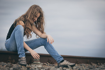 Image showing Portrait of young sad ten girl sitting outdoors at the day time.