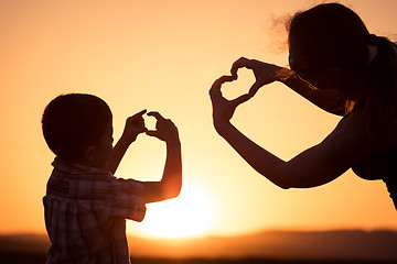 Image showing Mother and son walking on the field at the sunset time.