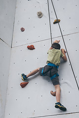 Image showing little boy climbing a rock wall outdoor.