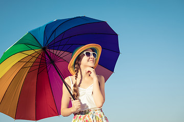 Image showing teen girl with umbrella standing on the beach at the day time.