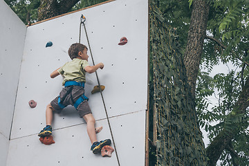 Image showing little boy climbing a rock wall outdoor.