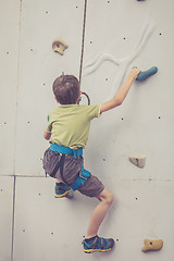 Image showing little boy climbing a rock wall outdoor.