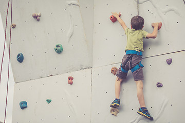 Image showing little boy climbing a rock wall outdoor.