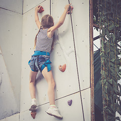 Image showing little girl climbing a rock wall outdoor.