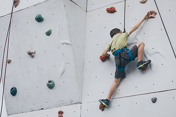 Image showing little boy climbing a rock wall outdoor.