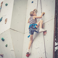 Image showing little girl climbing a rock wall outdoor.