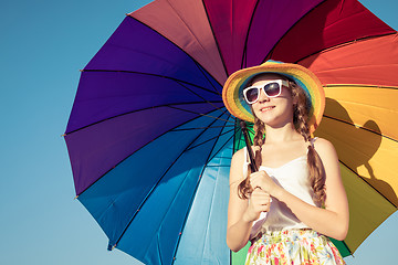 Image showing teen girl with umbrella standing on the beach at the day time.