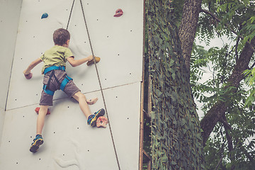 Image showing little boy climbing a rock wall outdoor.