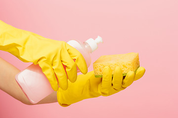 Image showing The woman\'s hand cleaning on a pink background. Cleaning or housekeeping concept