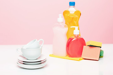 Image showing Several plates, a kitchen sponges and a plastic bottles with natural dishwashing liquid soap in use for hand dishwashing.