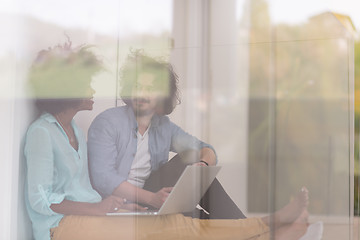 Image showing multiethnic couple using a laptop on the floor