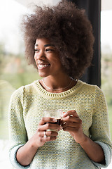 Image showing African American woman drinking coffee looking out the window