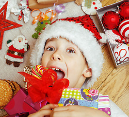 Image showing little cute boy with Christmas gifts at home. close up emotional happy smiling in mess with toys, lifestyle holiday people concept