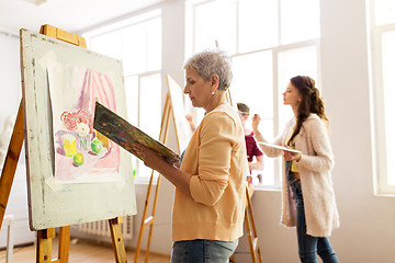 Image showing woman artist with easel painting at art school