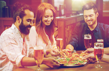 Image showing friends eating pizza with beer at restaurant