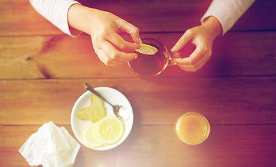 Image showing close up of woman adding lemon to tea cup