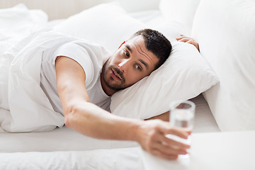 Image showing man in bed and reaching to glass of water at home