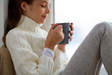 Image showing girl with tea mug sitting at home window