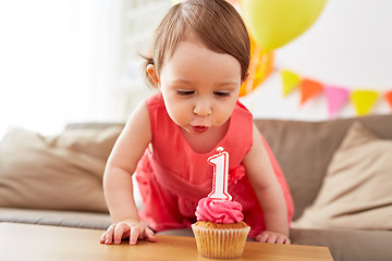 Image showing girl blowing to candle on cupcake at birthday