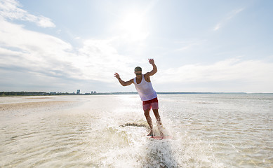 Image showing young man riding on skimboard on summer beach