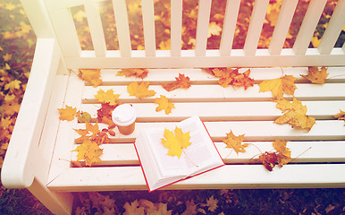 Image showing open book and coffee cup on bench in autumn park