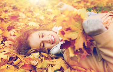 Image showing beautiful happy woman lying on autumn leaves