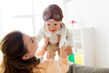 Image showing happy mother with baby wearing pilot hat at home