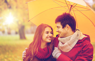 Image showing smiling couple with umbrella in autumn park