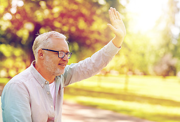 Image showing happy senior man waving hand at summer park