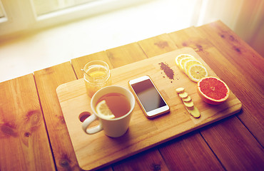 Image showing smartphone with cup of lemon tea, honey and ginger