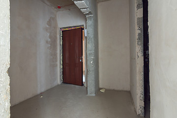 Image showing The entrance to the apartment is a new building, the front door and bare concrete and plastered walls