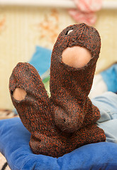 Image showing Woolen socks with huge holes on the legs of a man