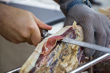 Image showing Slicing dry-cured ham prosciutto on the street market