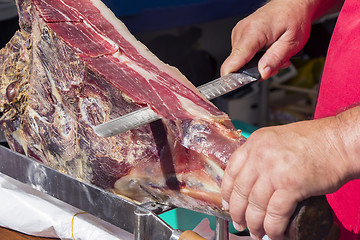 Image showing Slicing dry-cured ham prosciutto on the street market