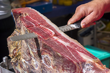 Image showing Slicing dry-cured ham prosciutto on the street market