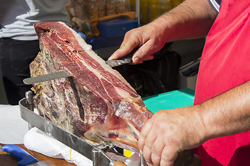 Image showing Slicing dry-cured ham prosciutto on the street market