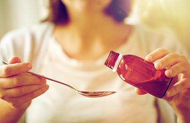 Image showing woman pouring medication from bottle to spoon