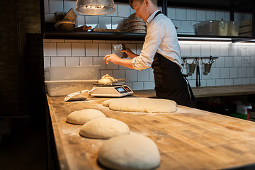 Image showing chef or baker weighing dough on scale at bakery