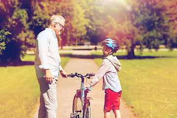 Image showing grandfather and boy with bicycle at summer park